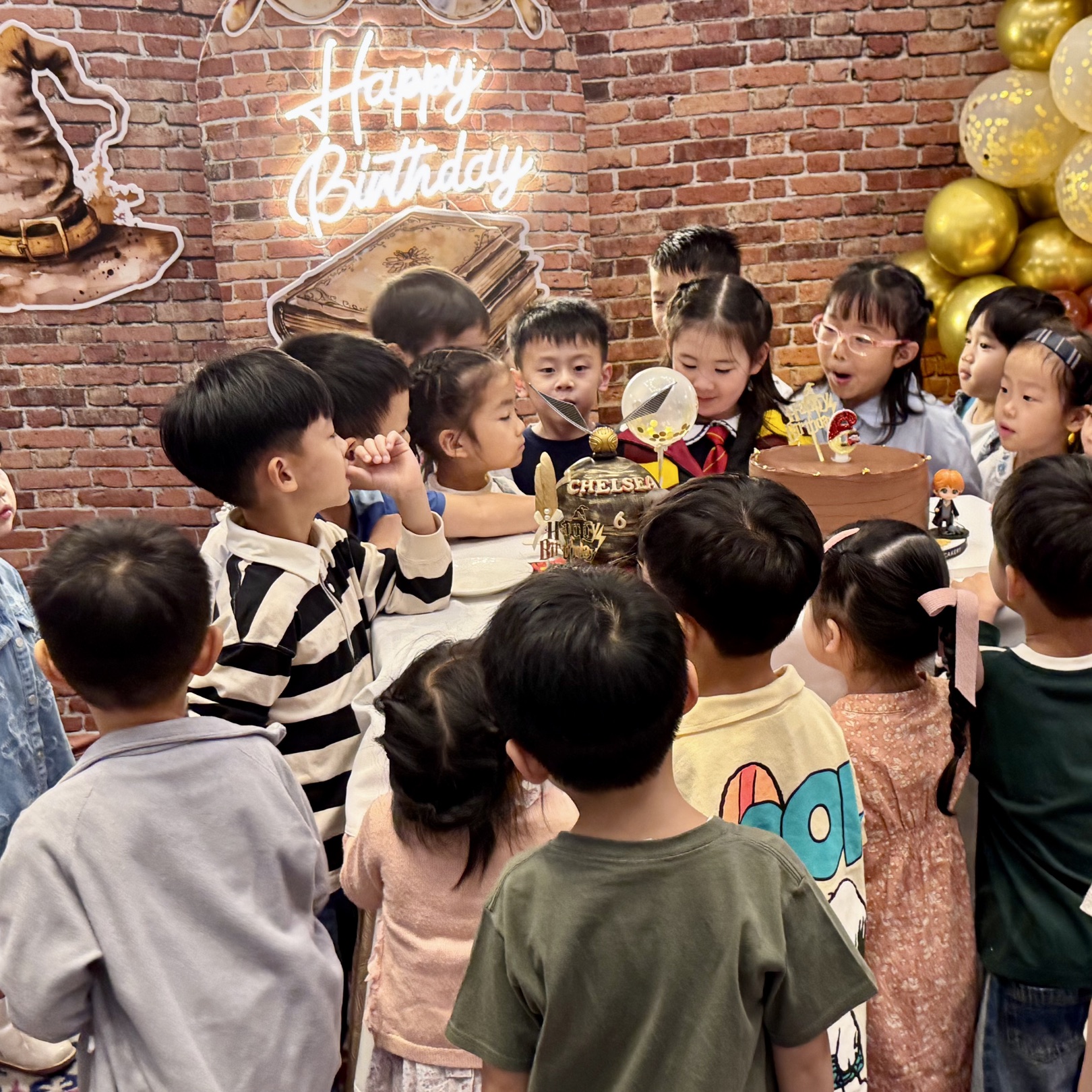 Children gathered around the birthday cake at a Newtonshow party