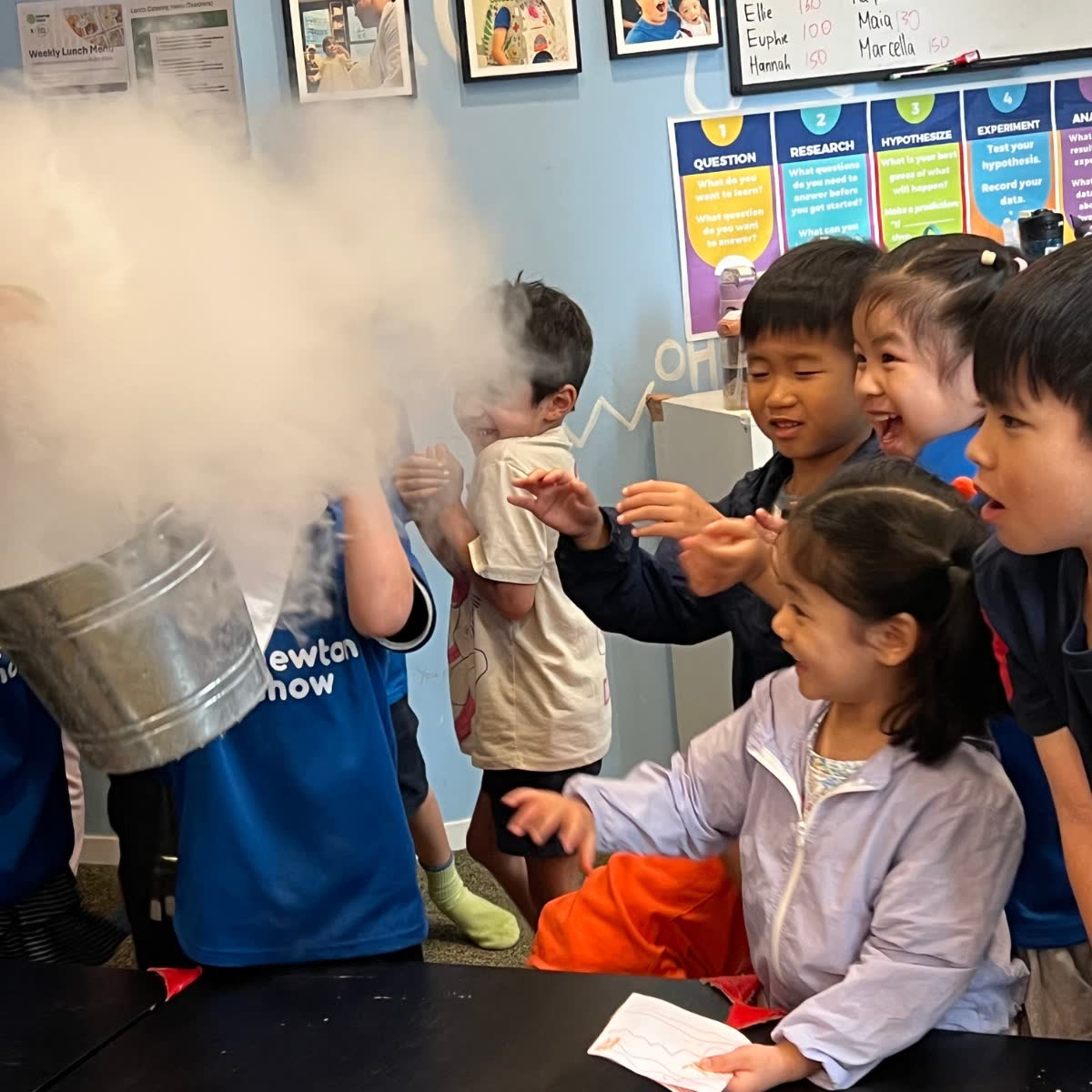 Children reaching into a cloud of dry-ice fog at a Newtonshow camp