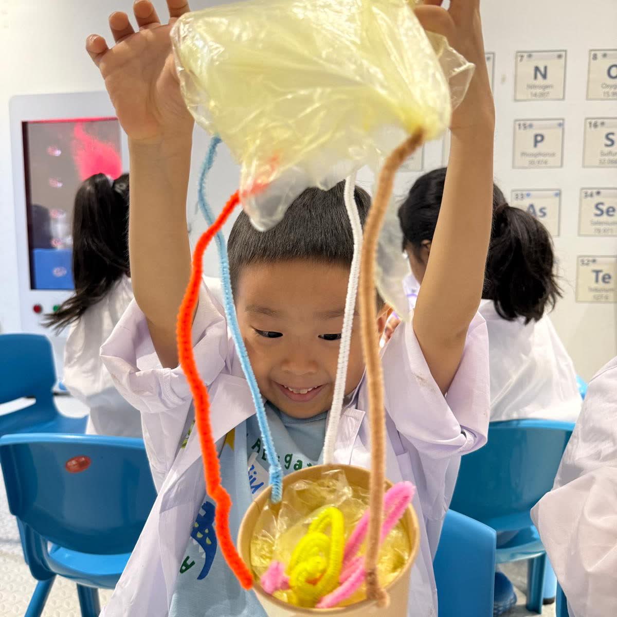 Boy holding up the inflated hot-air-balloon model he built at a Newtonshow Hong Kong camp