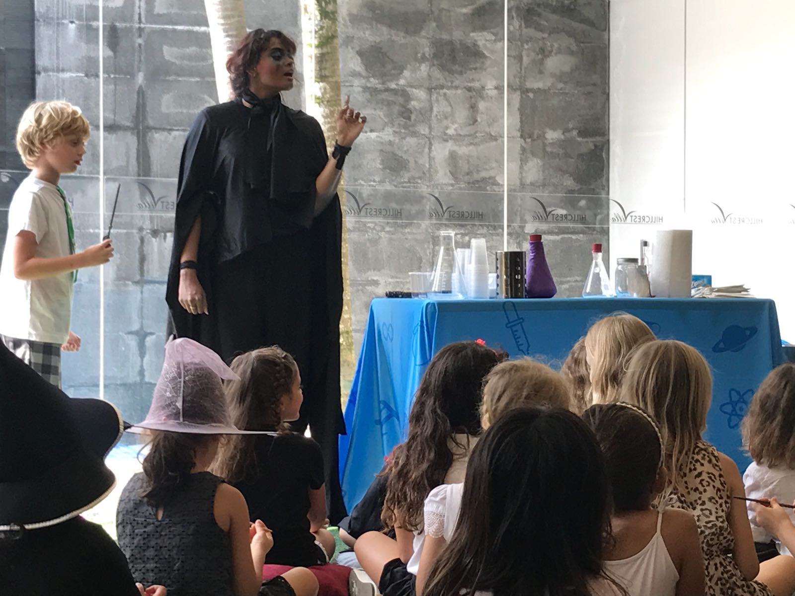 Wizard-costumed Newtonshow host performing science magic for seated party guests