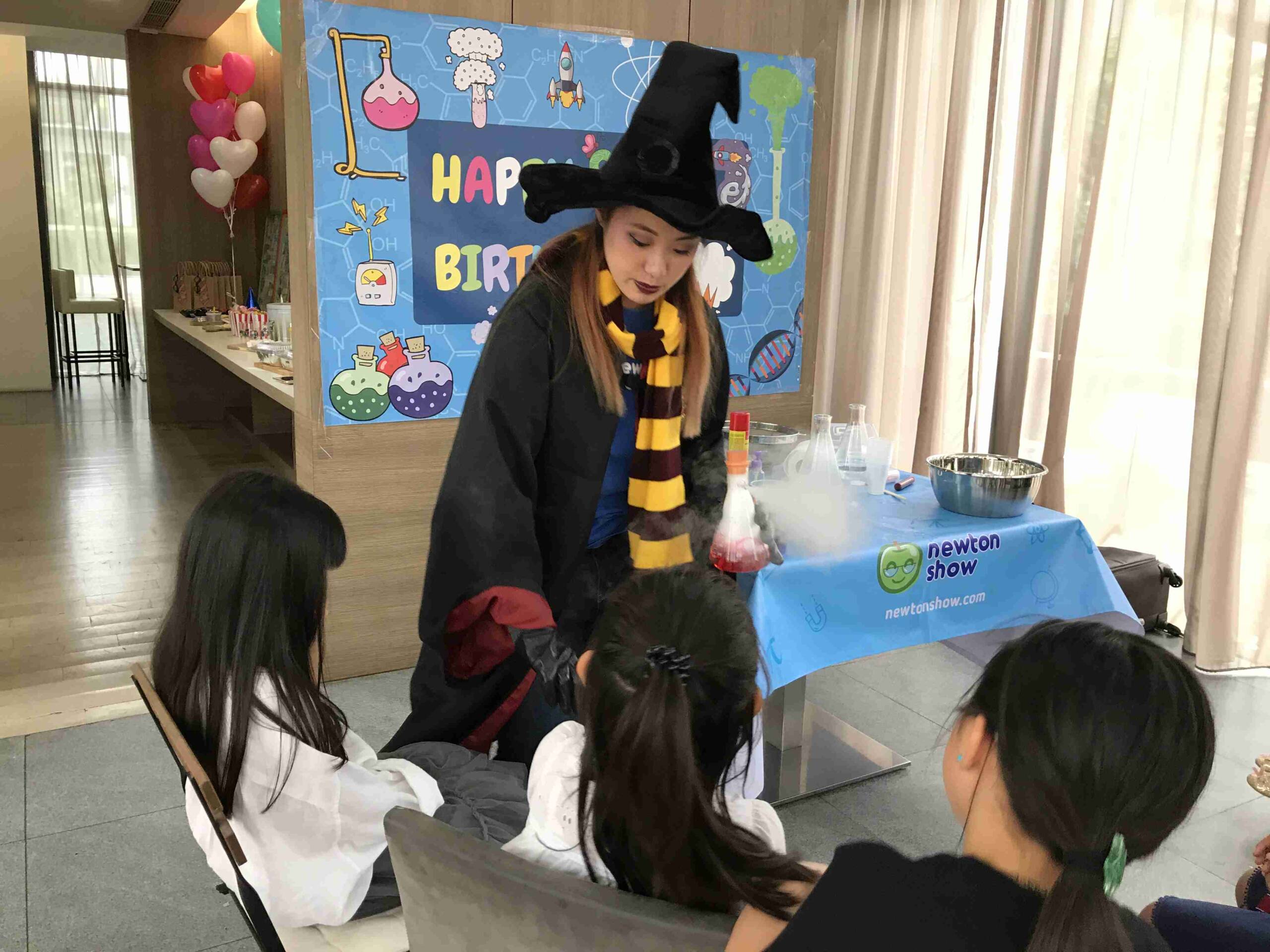 Wizard-costumed host leading a hands-on experiment with young guests at a Hong Kong birthday party