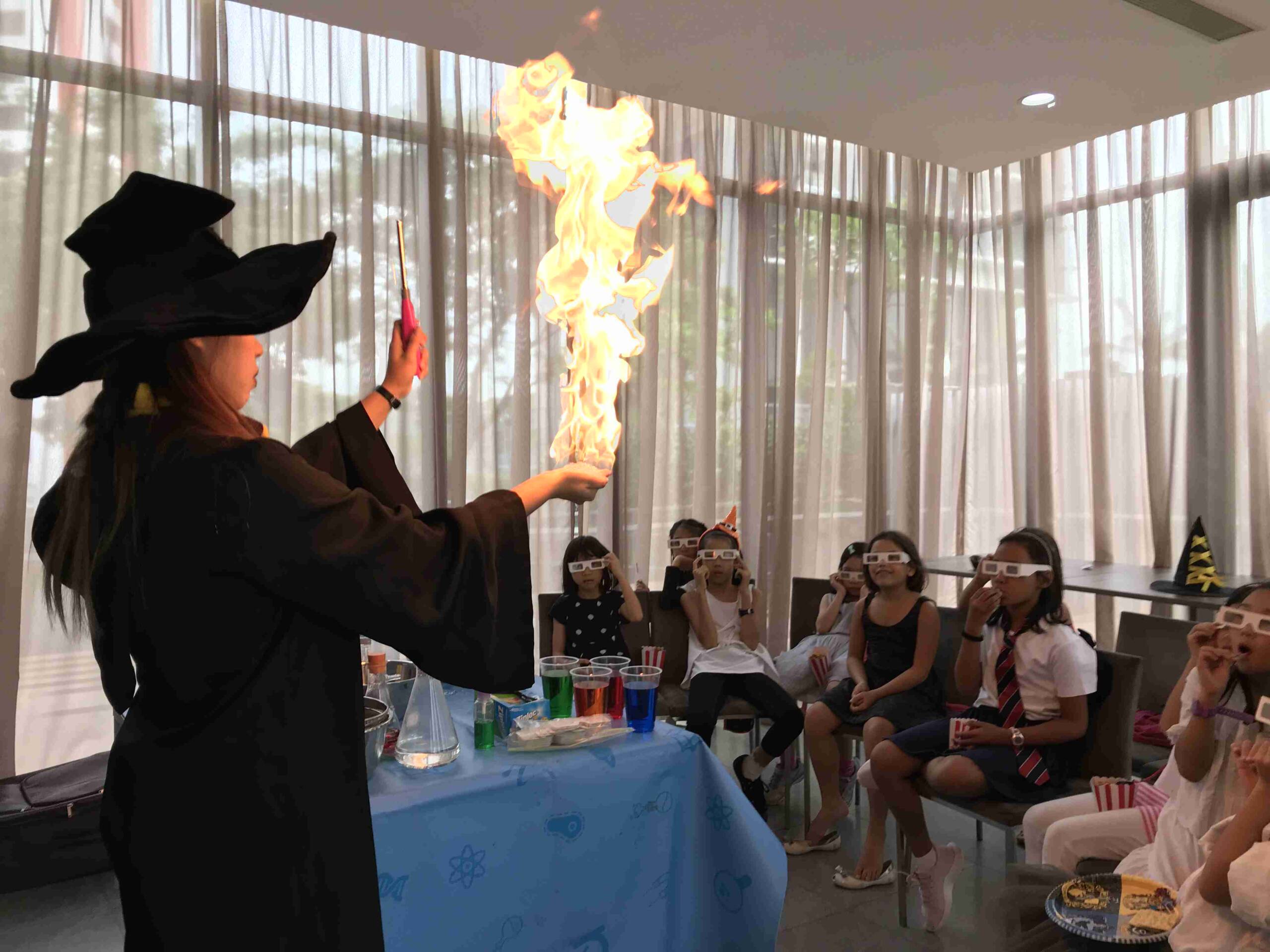Wizard-costumed Newtonshow host creating a burst of flame in front of amazed party guests