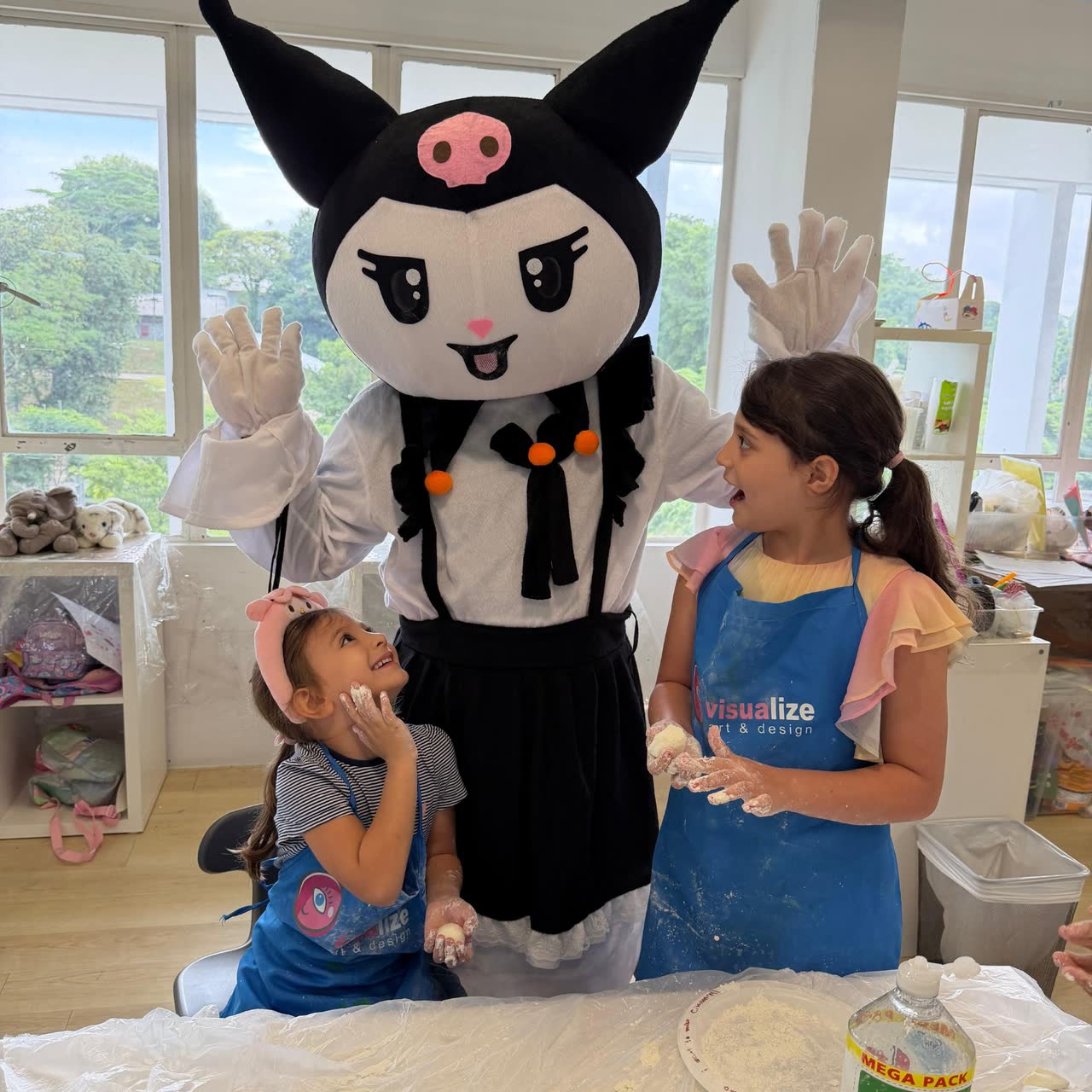 Two girls baking with a kawaii costumed character at a Newtonshow camp
