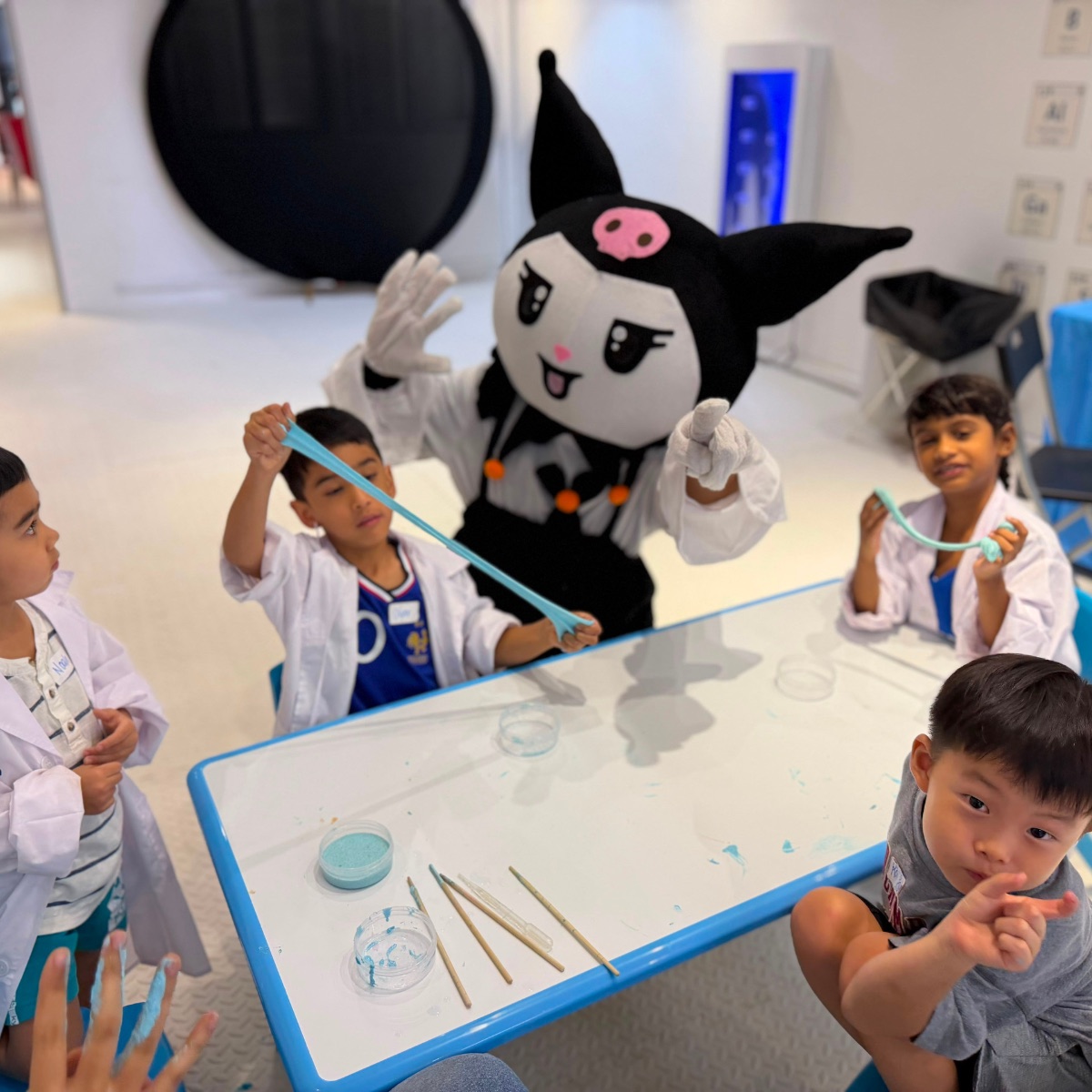 Young scientists running a slime experiment with a costumed character at Newtonshow