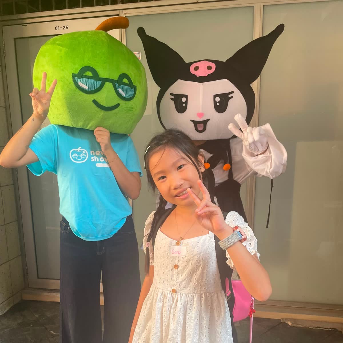 Two Newtonshow mascots posing with a camper outside a Hong Kong campus