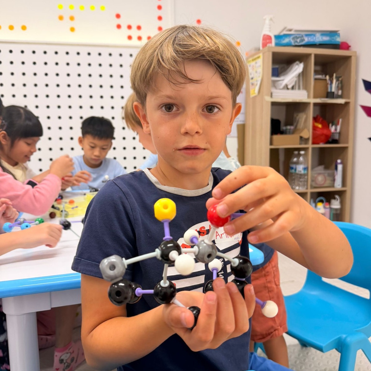 Boy holding a molecular model he built at a Newtonshow camp