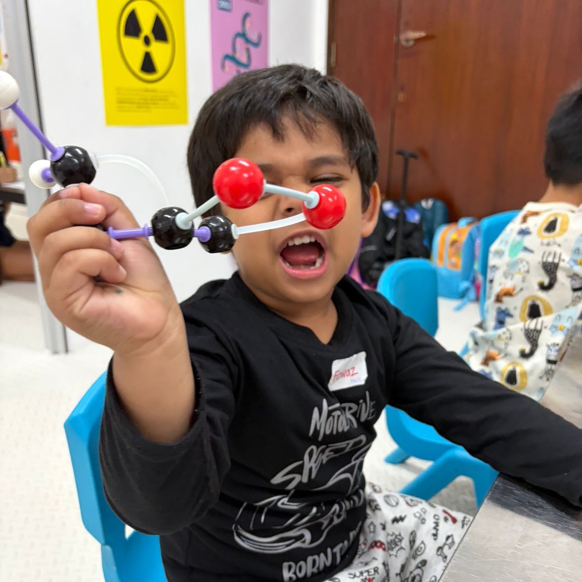 Delighted boy holding up the molecular model he built at a Newtonshow Hong Kong camp