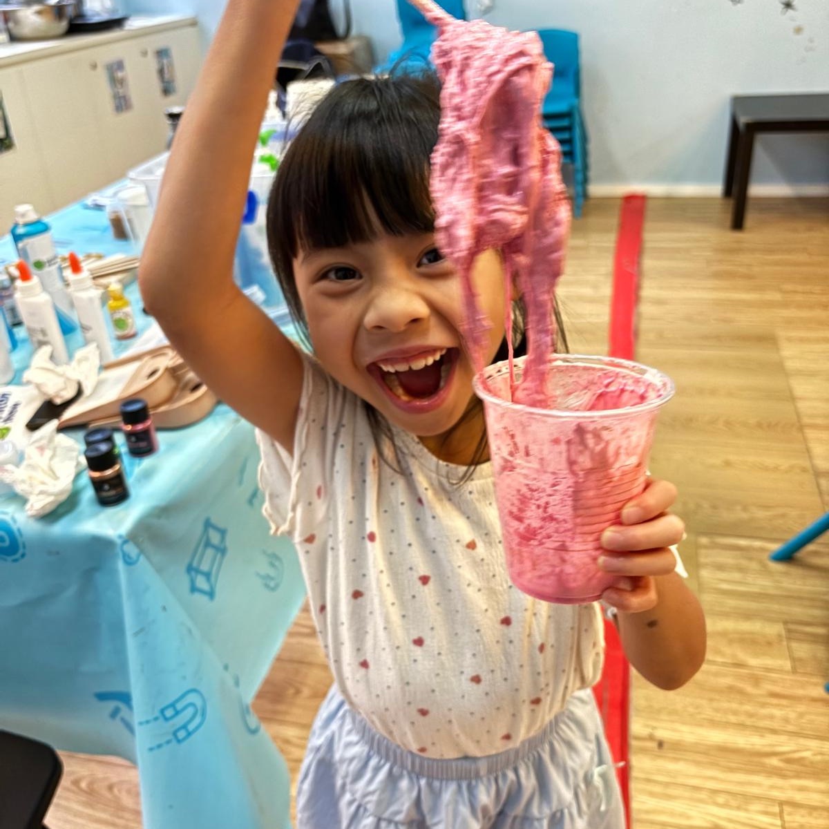 Girl holding a long strand of bright pink slime she made at Newtonshow