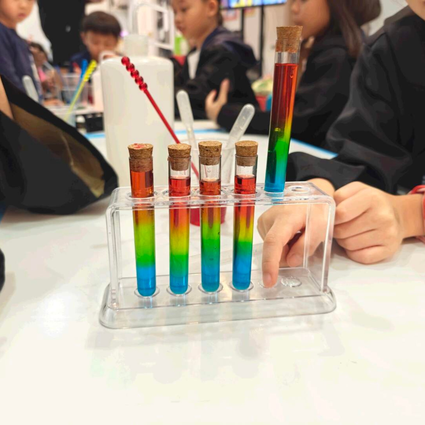 Rack of rainbow-layered potion test tubes made by party guests