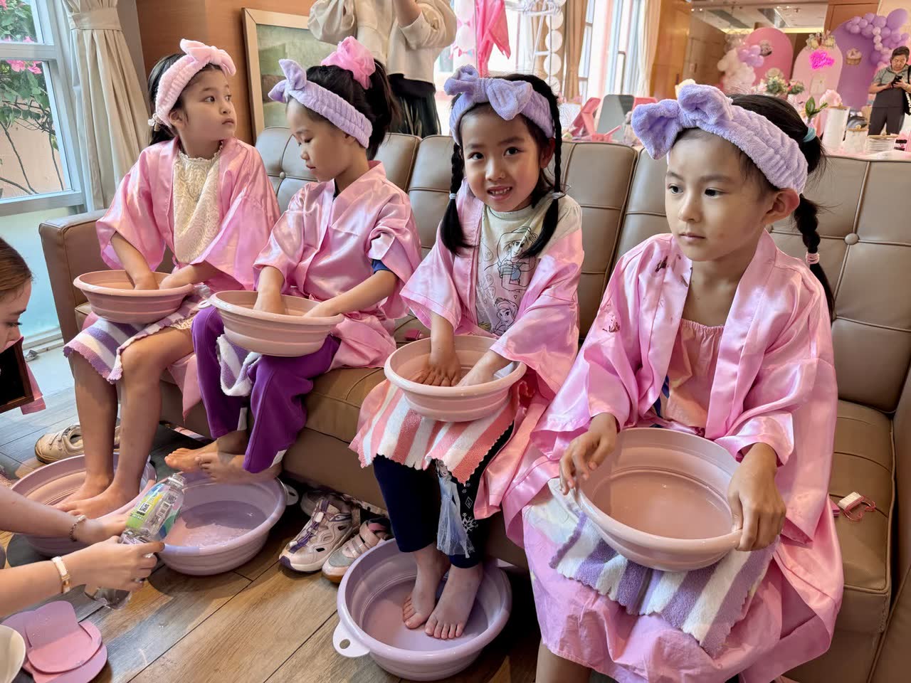 Girls in pink robes with foot spa bowls at a Newtonshow kids spa party in Hong Kong