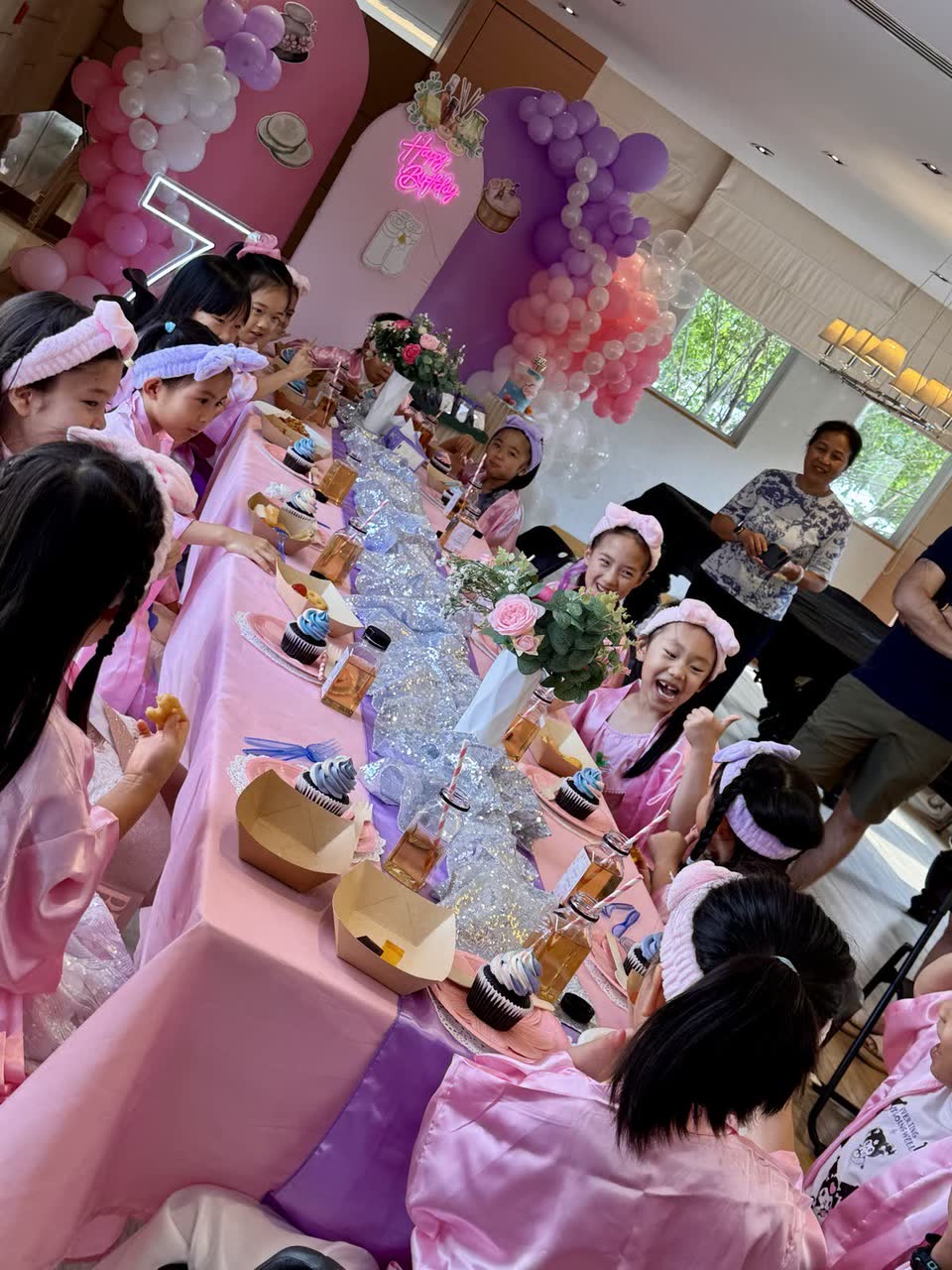 Long pink spa party table with girls in robes and headbands at a Newtonshow party