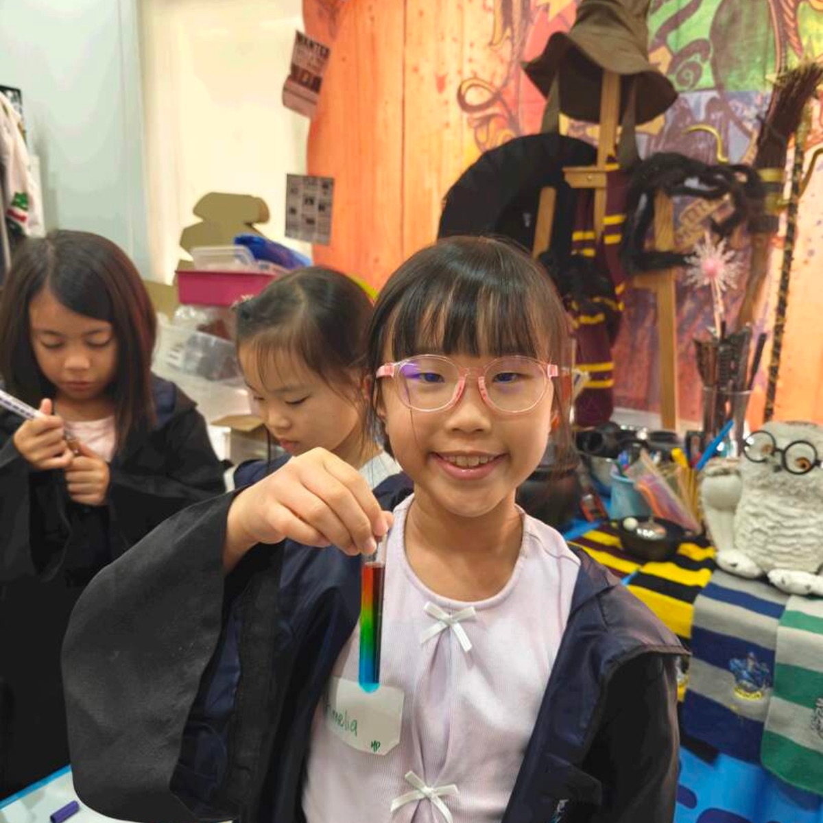 Girl holding a rainbow-layered potion tube at a Newtonshow session